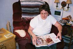 Women (Wendy Wells) sitting in chair reading large book. 