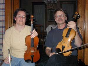 Woman (Beth Preheim at left) and man (Bill Peterson) sit side-by-side with fiddles.