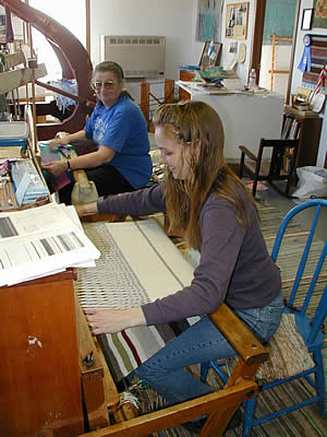 Two women (Annikki Marttila (rear) and  Marianne Marttila-Klipfel) weave on large loom.