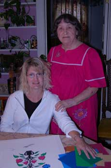 Karen Wunder-Colestock (seated at table) and Leona Barthle (standing at right, behind) working on a wycinanki piece