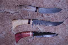 Three knives in a vertical row. Steel blades facing right, wooden handles facing left. 
