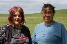 Two women (Jasmine Terkildsen with master artist Tilda St. Pierre) standing together in an open landscape