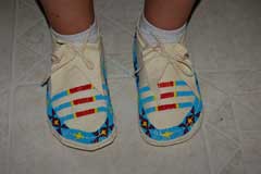 Pair of beaded moccasins  with sky blue, red, yellow, navy, and gold beads in a pattern across the top and above the sole