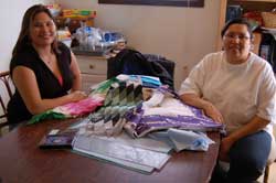 Two women at a table with quilting materials. Kristen Turning Heart at left. Renee Turning Heart at right. 