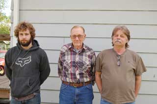 Three men standing in a row in front of a building. Josh Scott (at left), Dwight Lamb (at center), and Bill Peterson (at right).