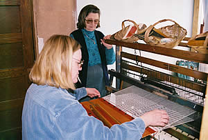 Two women (Annikki Marttila and Peggy Worthy) work together on loom.